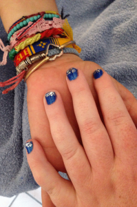 Siobhan's hand in Juliana's hand showing cobalt blue nail polish with silver glitter tips.